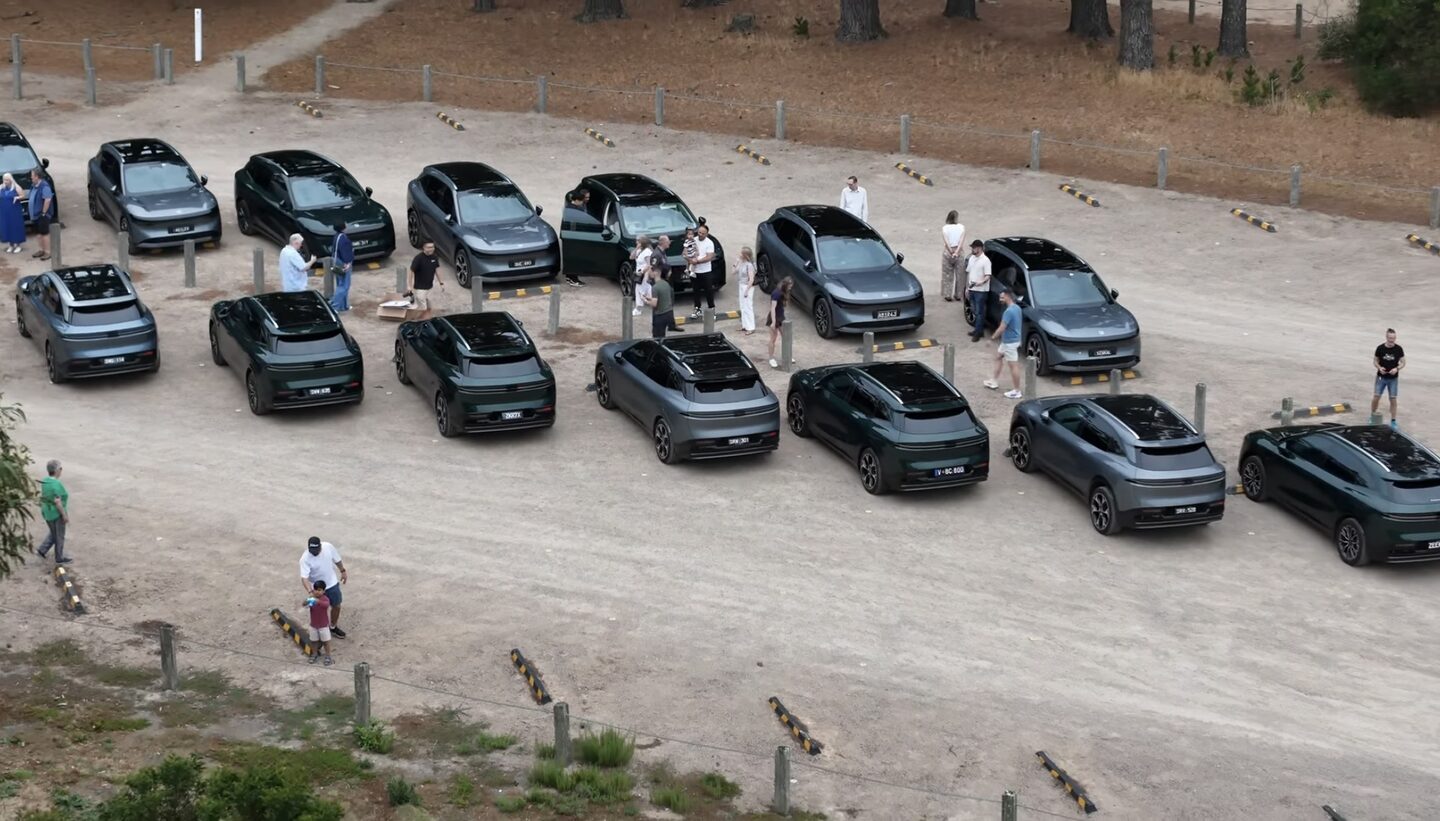 An aerial view of a large line-up of ZEEKR vehicles parked together while owners chat nearby.